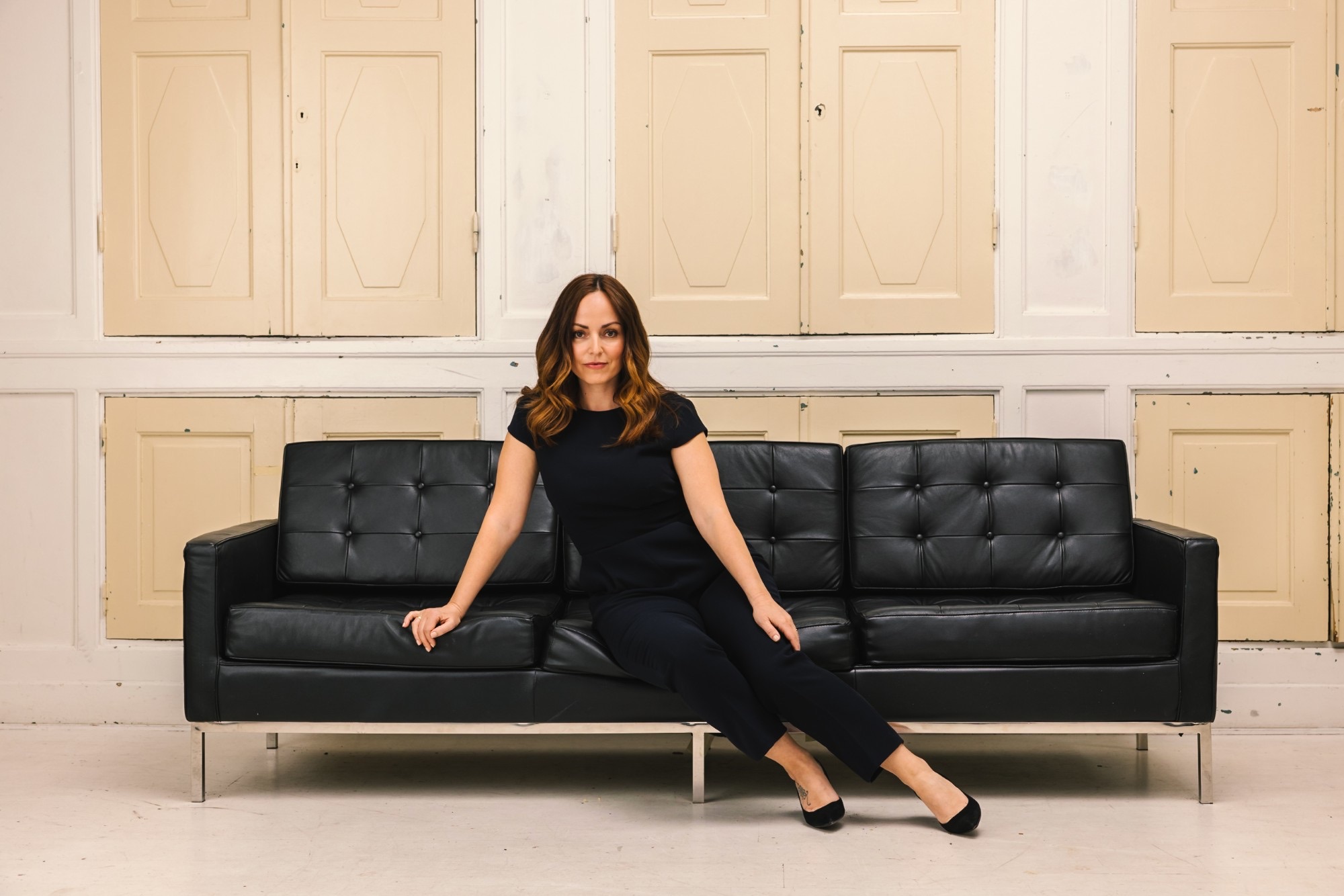 Fernanda Lind seated on a black leather sofa, looking into the camera
